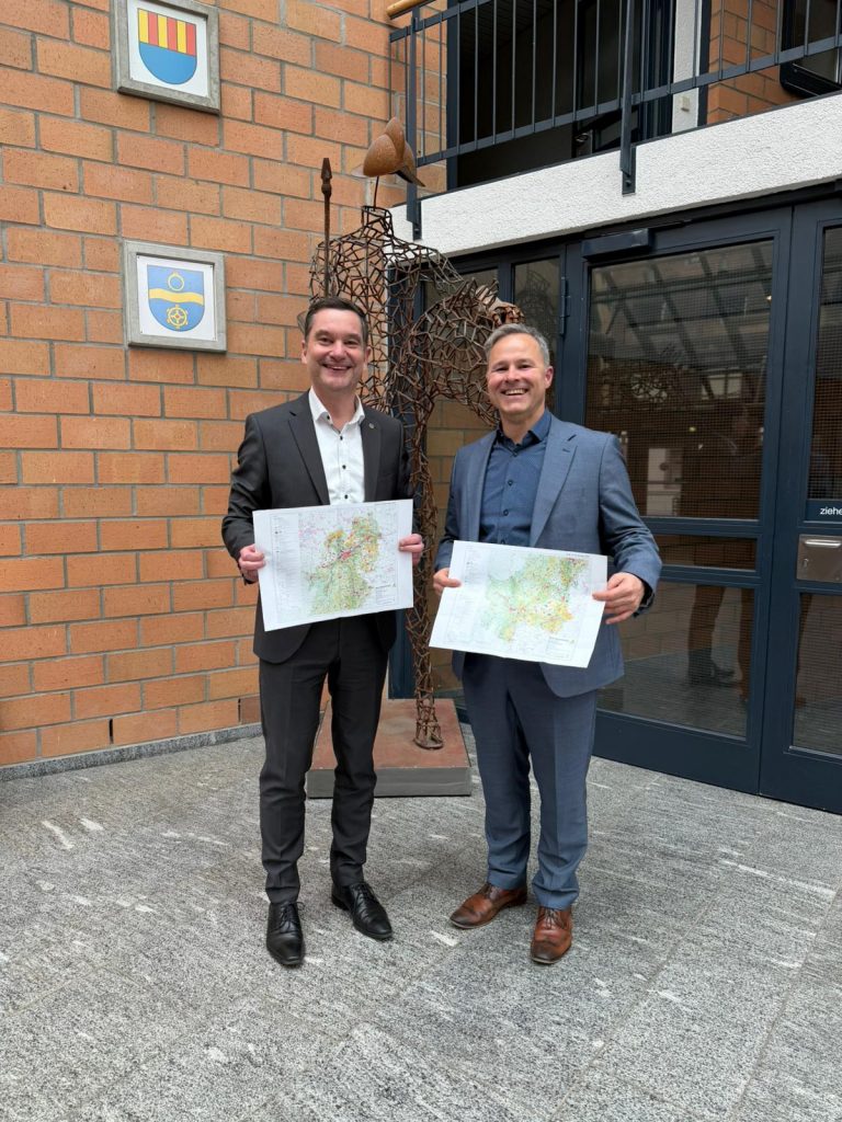 Zwei Männer halten die Karten des Teilregionalplans Windenergie.
