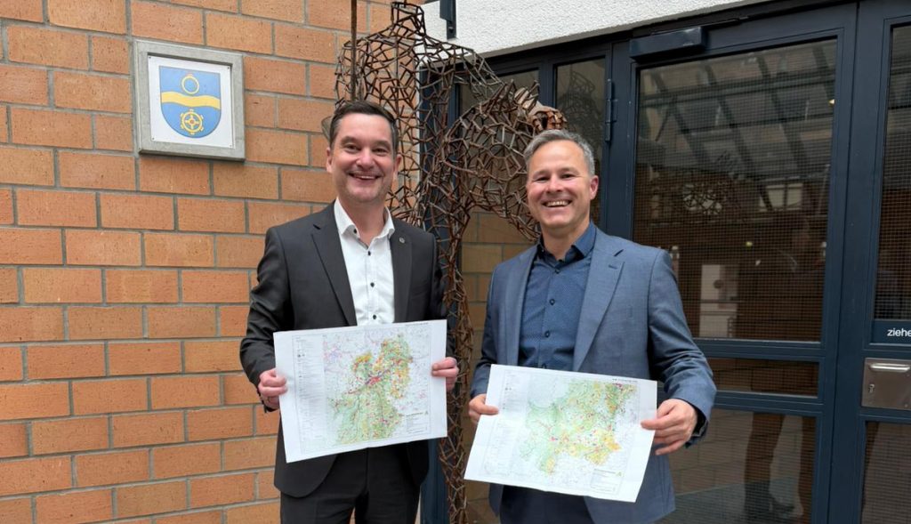 Zwei Männer halten die Karten des Teilregionalplans Windenergie.
