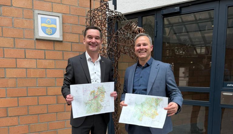 Zwei Männer halten die Karten des Teilregionalplans Windenergie.